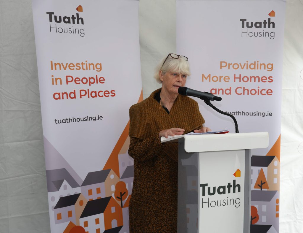 Angela Murphy speaking at podium in front of Tuath banners