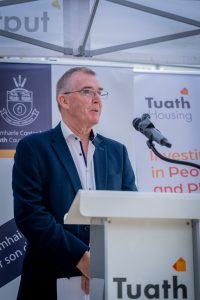 Gerry Flynn speaking at the event at podium in front of roller banners 