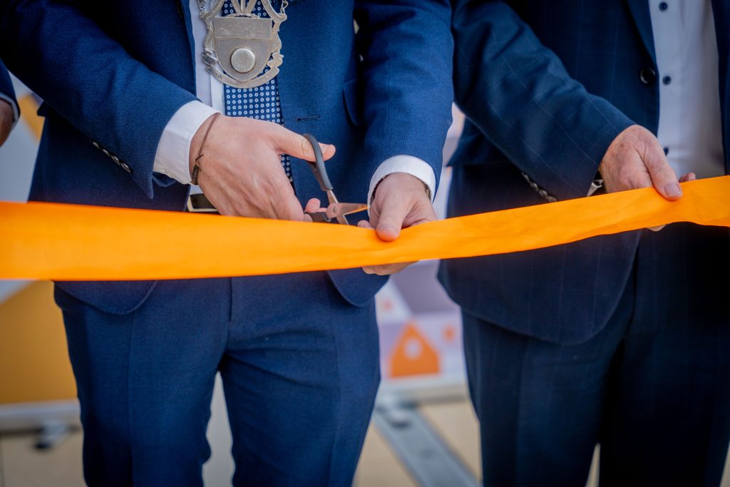 close shot of orange ribbon being cut with scissors at event
