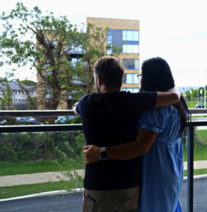 couple standing on balcony with backs to camera