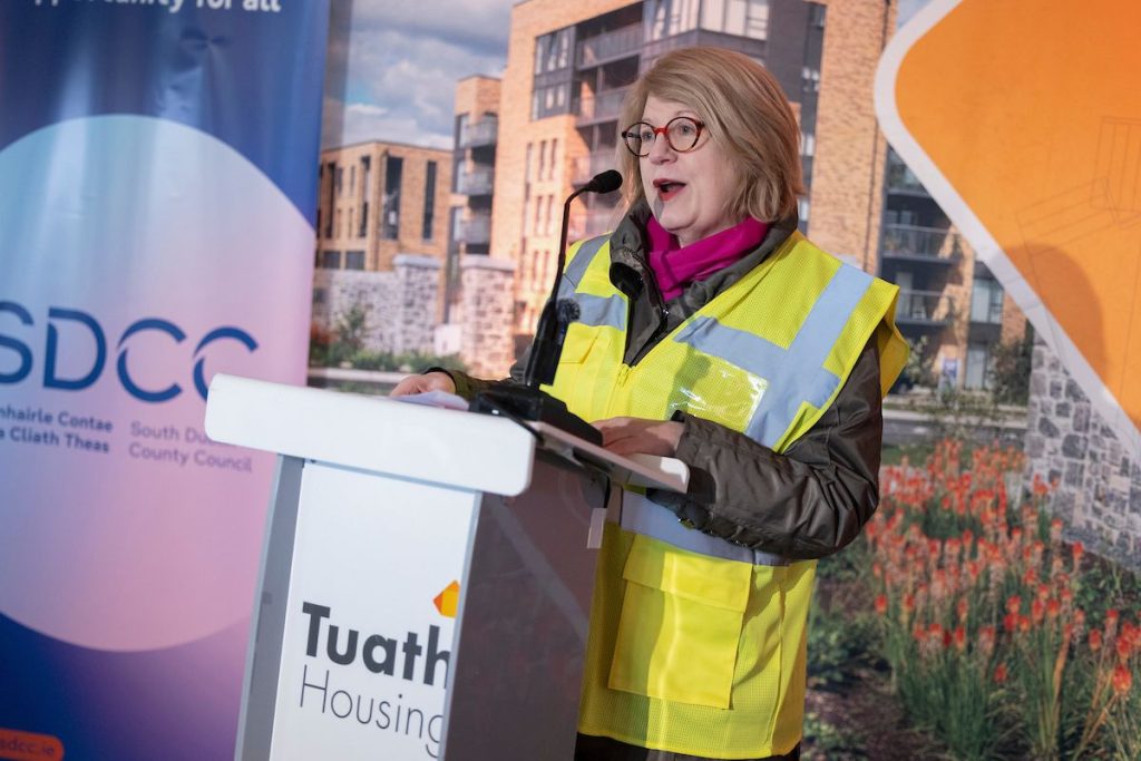 Marian Jennings speaks at podium in front of stakeholder branding