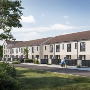 Exterior view of the terraced homes at Blessington Demesne, with landscaped green space and a family walking past